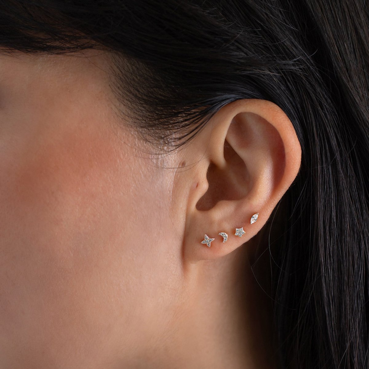 Sterling silver zirconia star flat back stud shown in an ear stack on a model's lobe