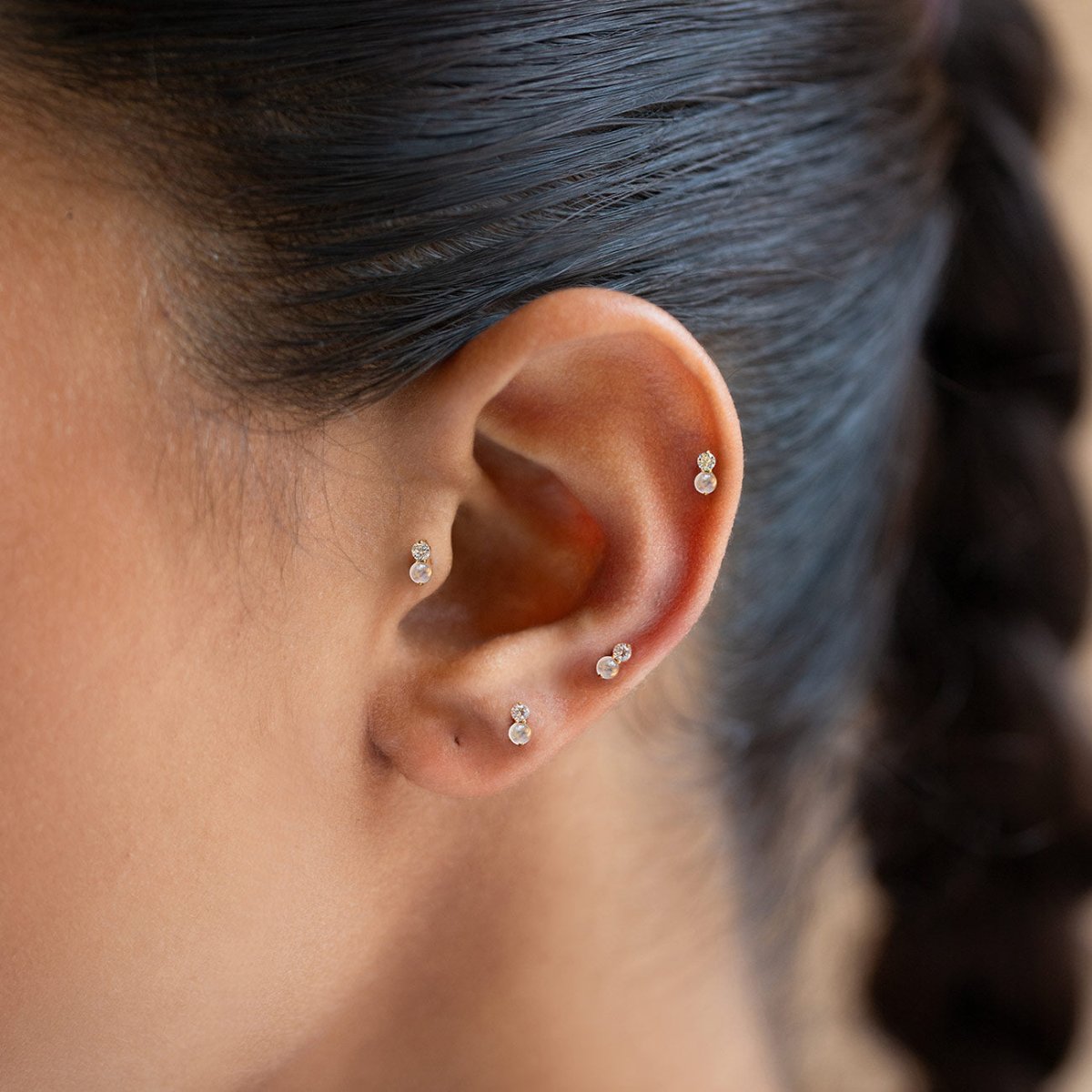 Gold pavé flat back stud earrings with a round crystal and an opal gemstone, shown on a model's ear |#Gemstone_White Opal