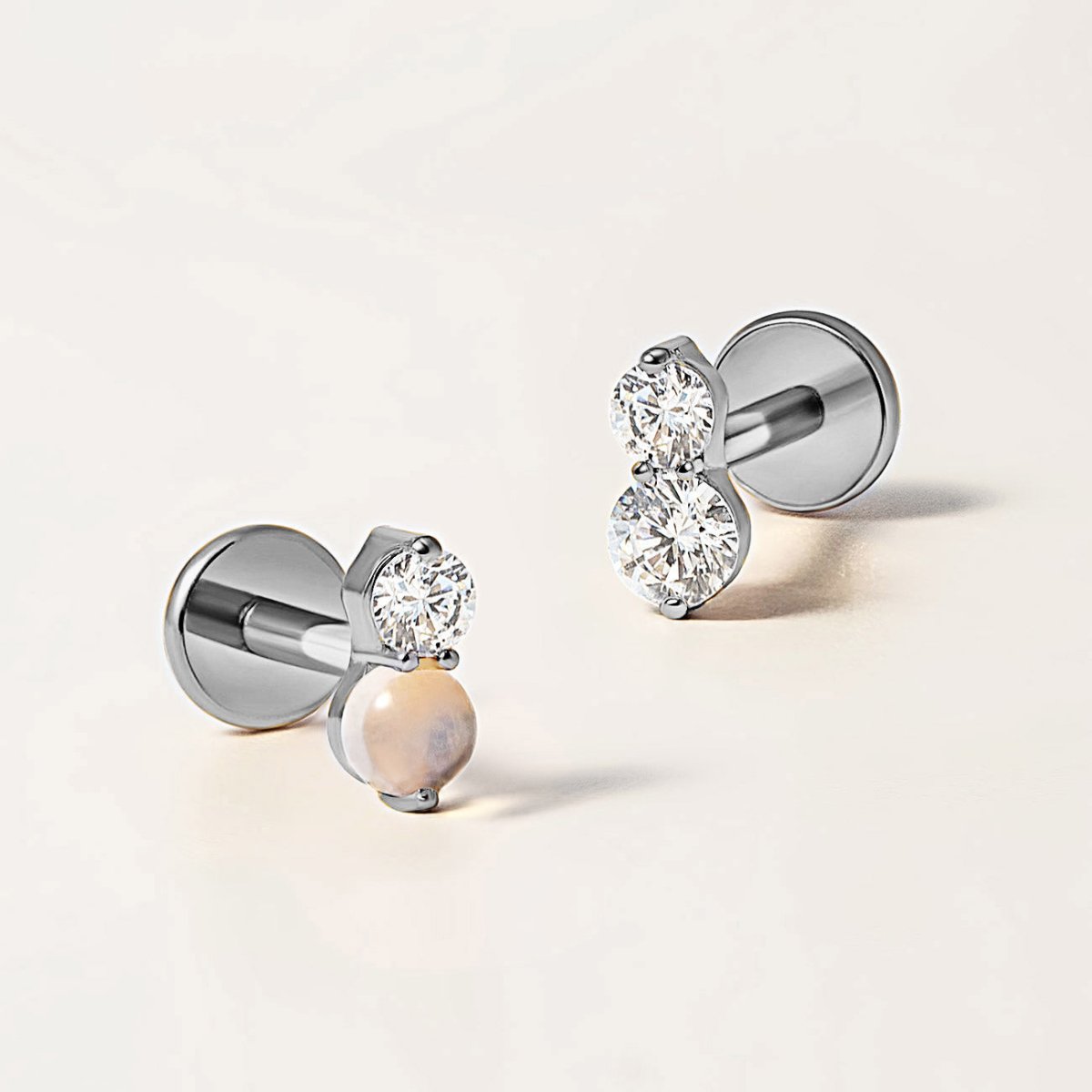 Close up of two titanium flat back earrings and gemstone variant options, Zirconia and opal