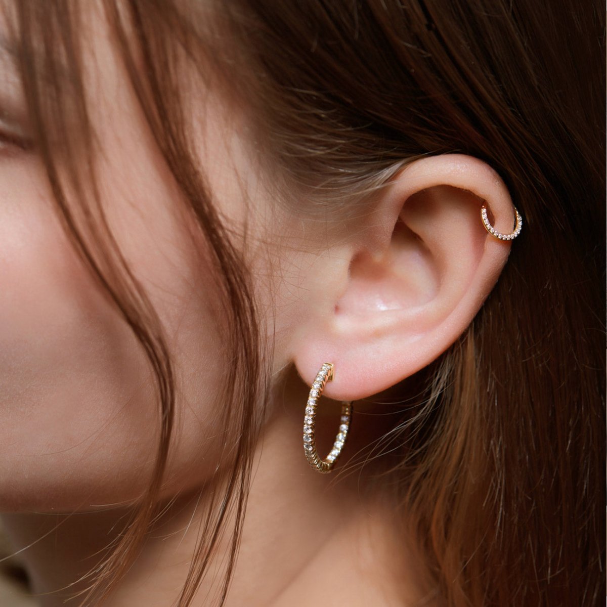 14K gold front pavé hoop with white zirconia in the lobe and a pavé helix hoop, shown on a model's ear