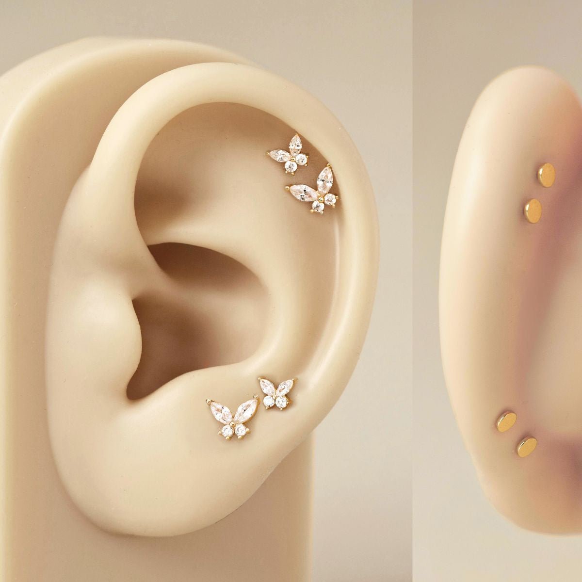 14K gold butterfly flat back studs set with clear stones, shown on a model's ear with a plain-stud pair