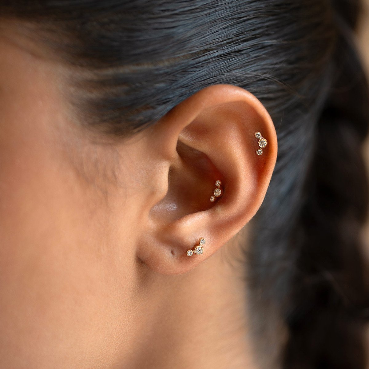 14K gold curved trio bezel flat back stud earrings, shown on a model
