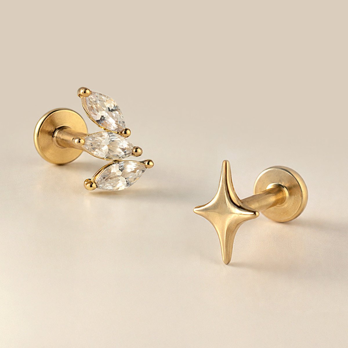 14K gold tiny star flat back stud beside a marquise clear-stone cluster stud, close-up detail