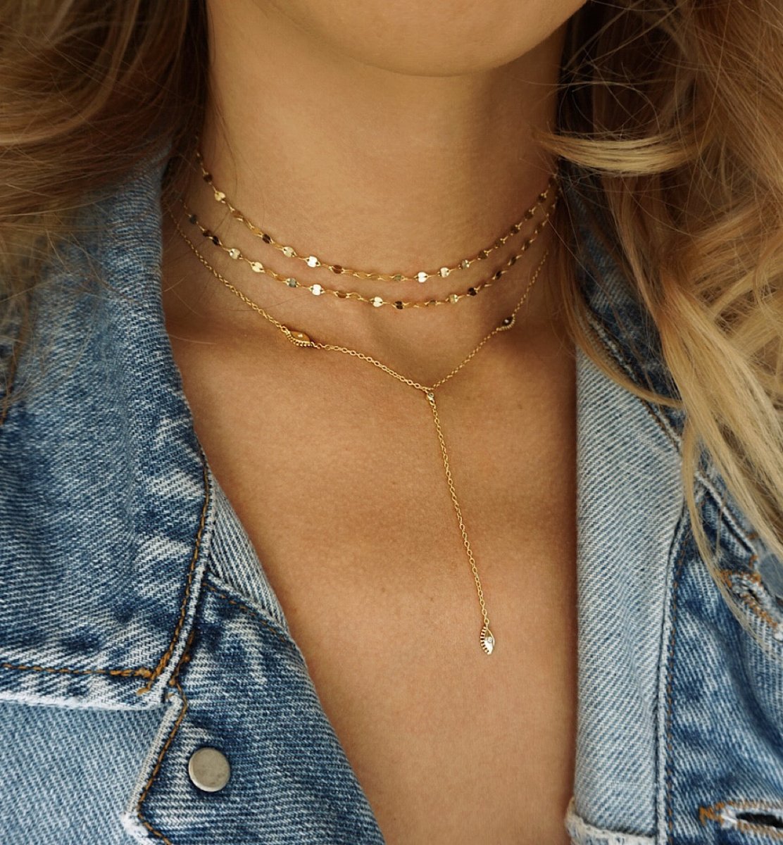 Gold vermeil evil eye lariat necklace layered with chokers, shown on a model's neckline