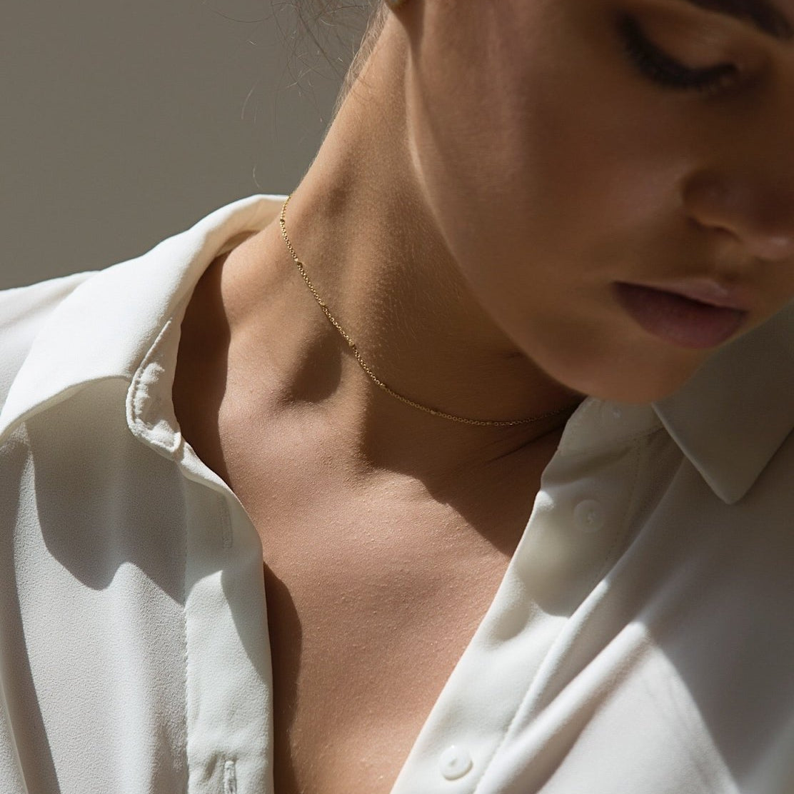 Gold vermeil beaded satellite chain choker, shown on a model's neckline