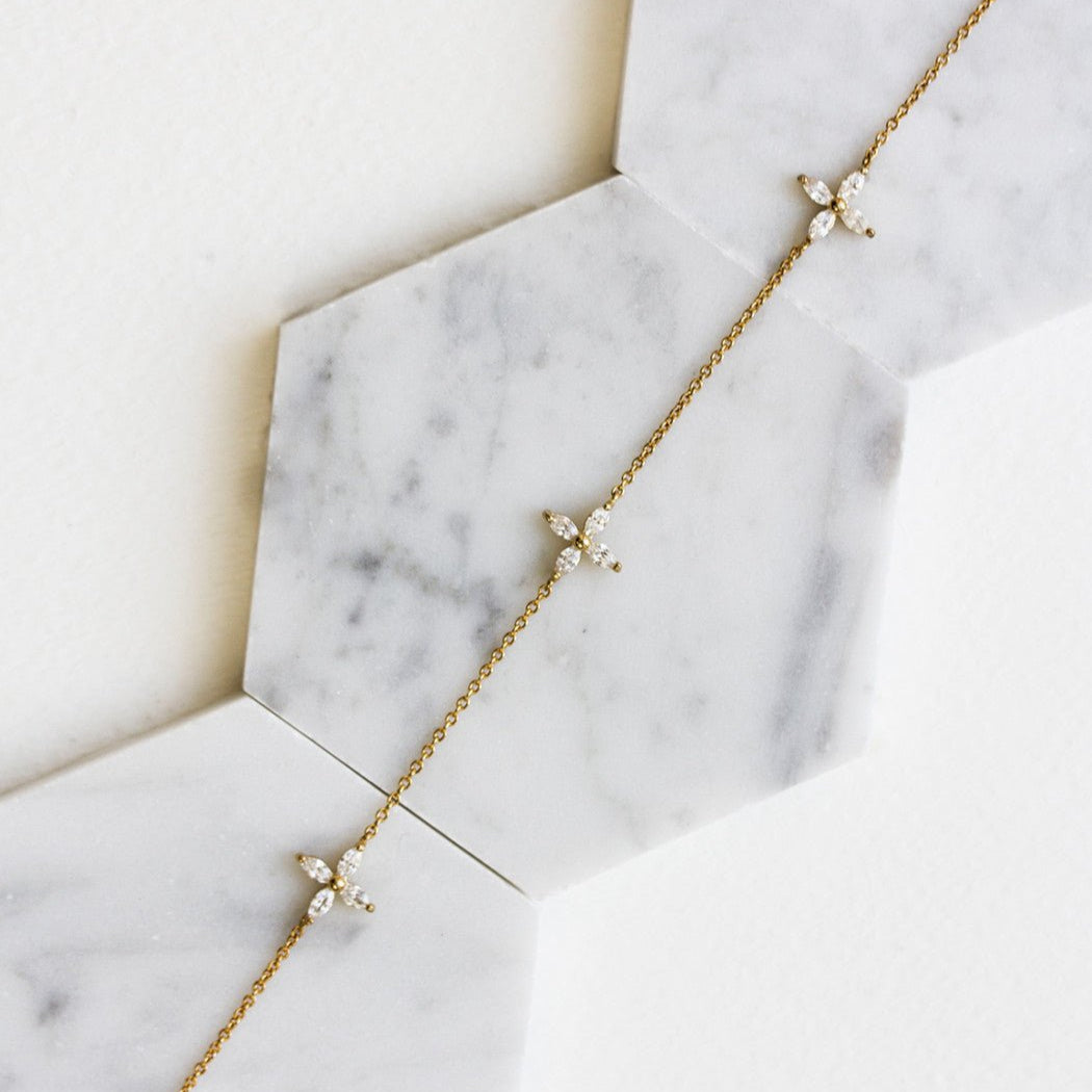 Gold vermeil clear crystal flower choker shown on a model's neckline above a longer chain