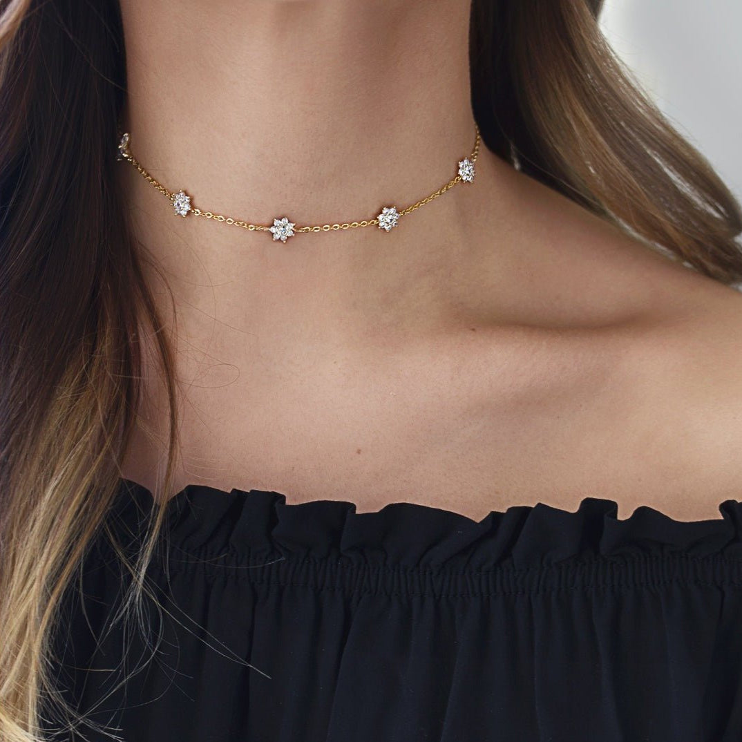 Gold vermeil white zirconia choker with pavé flower stations, shown on a model's neckline