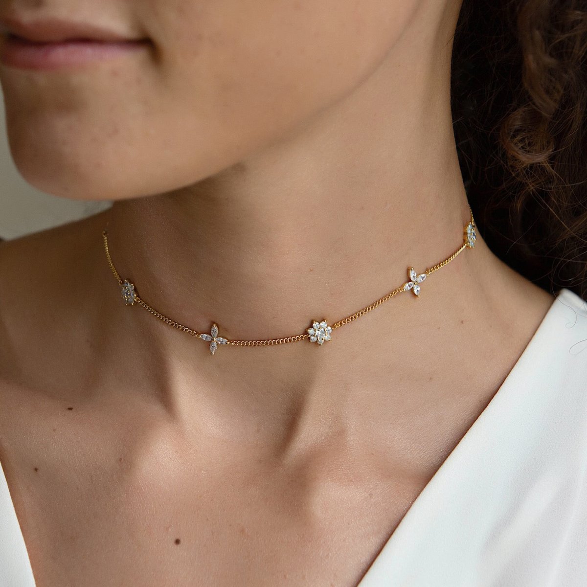 Gold vermeil choker with scattered clear crystal flowers, shown on a model's neckline