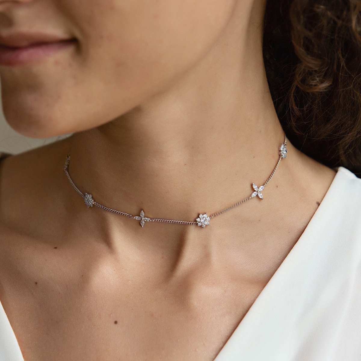 Sterling silver choker with clear crystal flower stations, shown on a model's neckline