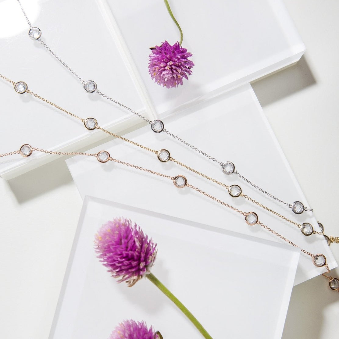 Rose gold vermeil station choker with clear stones, with gold and silver versions laid on white tiles