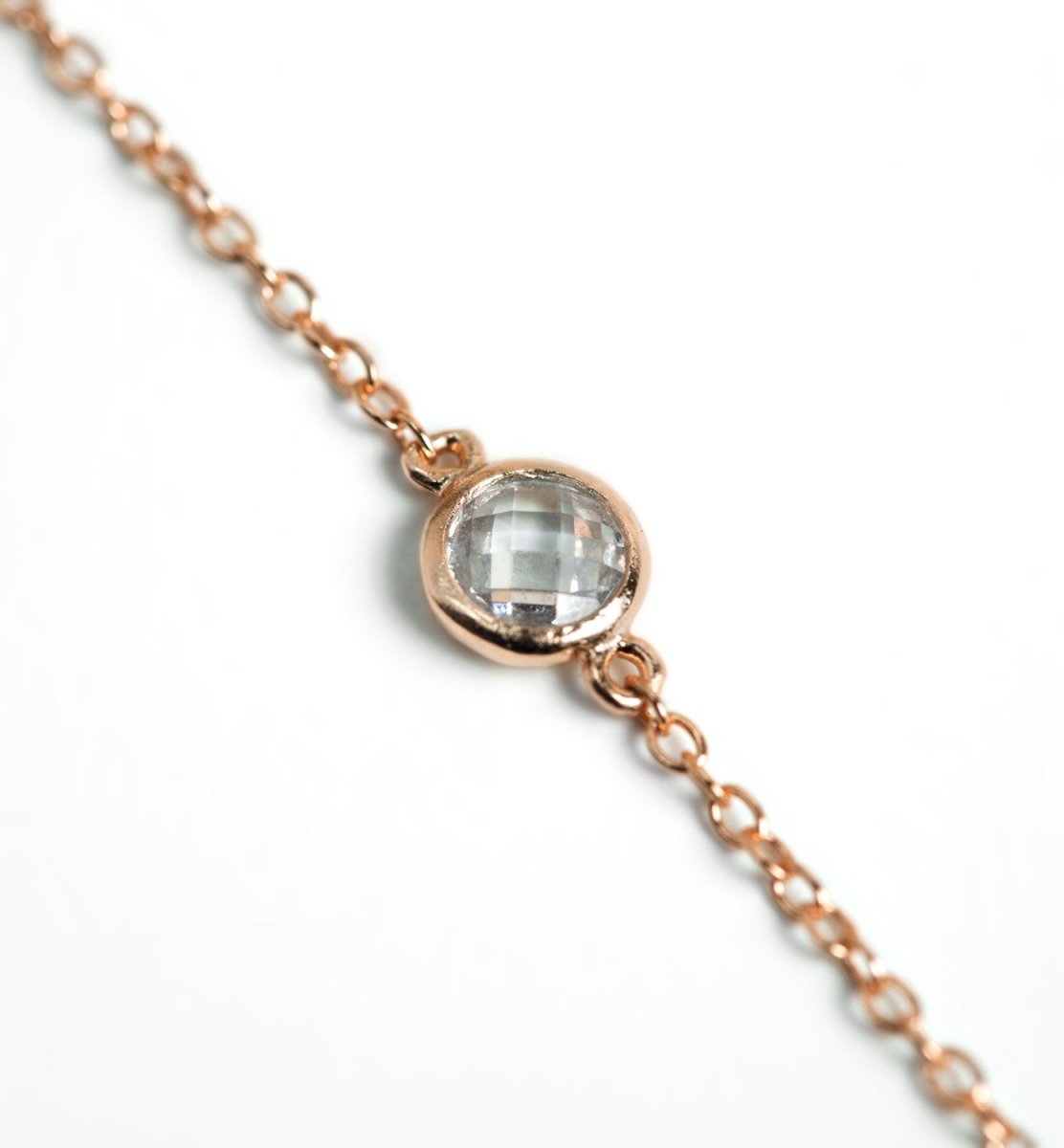 Rose gold vermeil station chain with a round clear stone, close-up detail on a white background