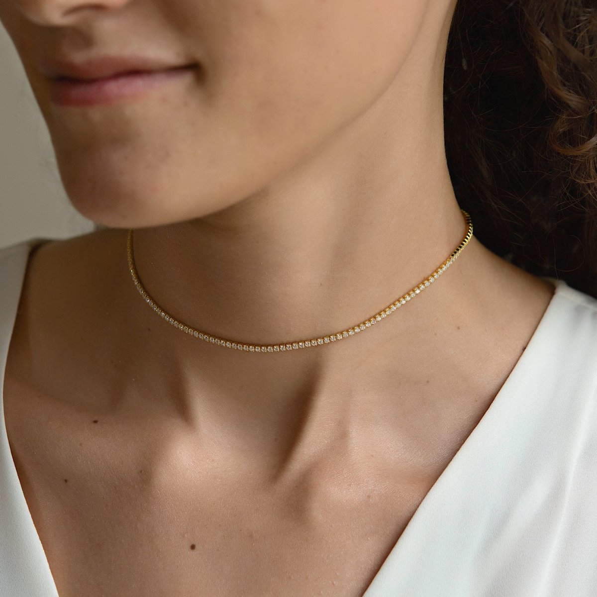 Gold vermeil crystal choker with round clear stones, shown on a model's neckline