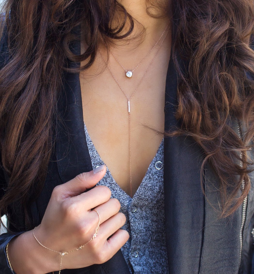 Rose gold vermeil bar lariat necklace layered on a model's neckline over a gray top