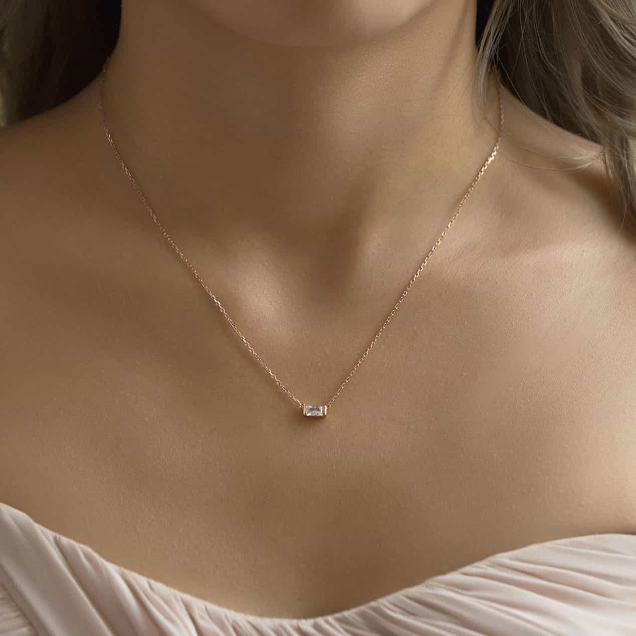 Rose gold vermeil baguette necklace with a clear white zirconia pendant, shown on a model