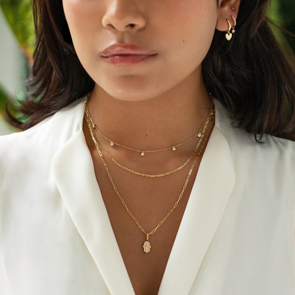 Gold vermeil pavé hamsa charm with white zirconia, shown on a paperclip chain on a model's neckline