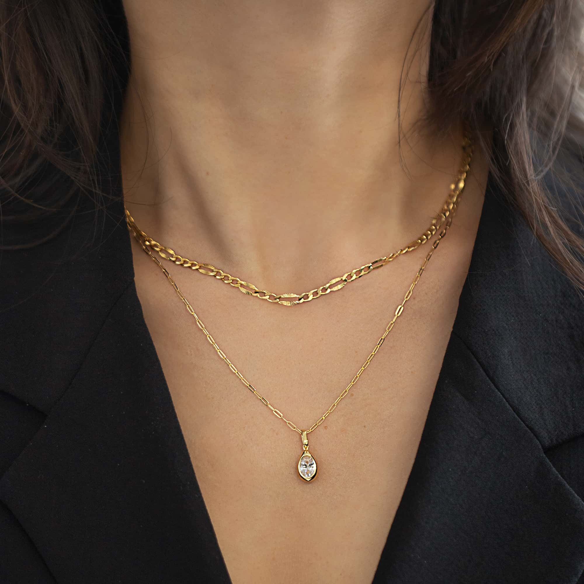 Gold vermeil pear-shaped pendant with a clear stone on a paperclip chain, shown on a model's neckline