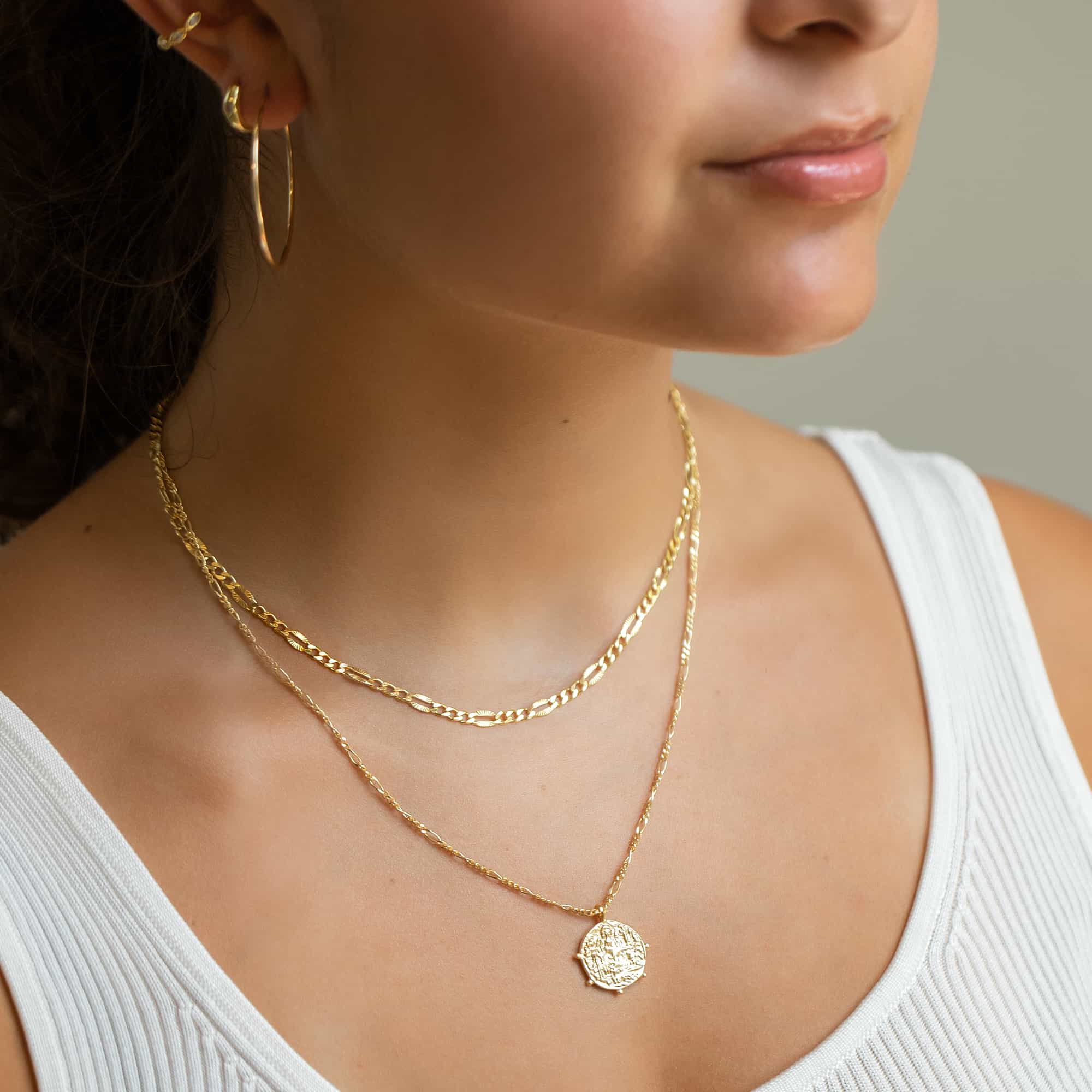 Gold vermeil Grecian coin pendant on a figaro chain, with hoop earrings, shown on a model