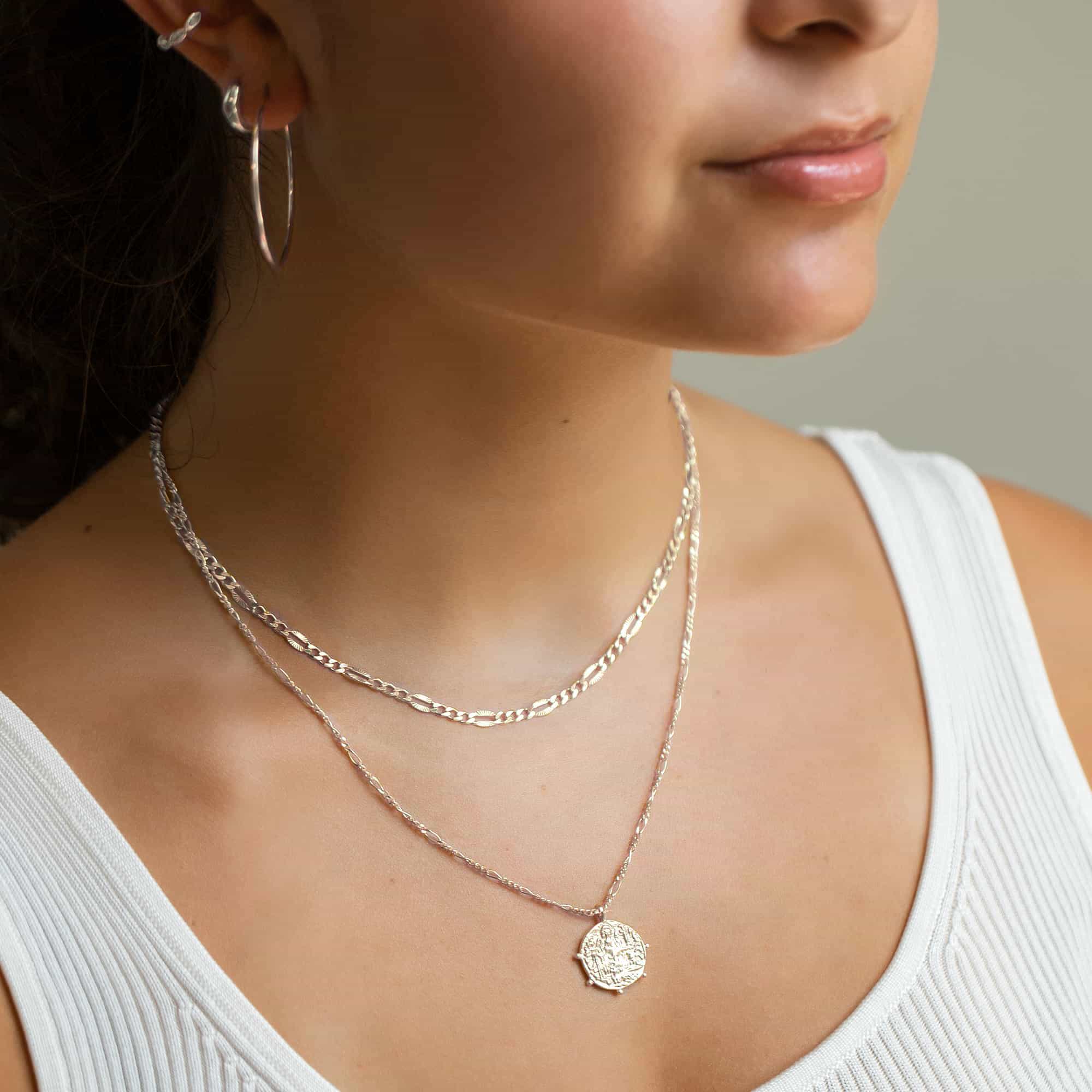 Sterling silver Grecian coin pendant on a figaro chain, shown layered on a model's neckline