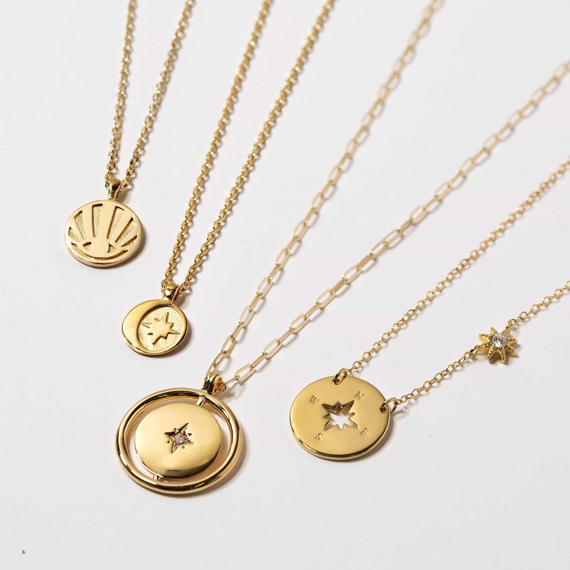 Gold vermeil Northern Star disc pendant, shown with other star and moon pendants on a white background