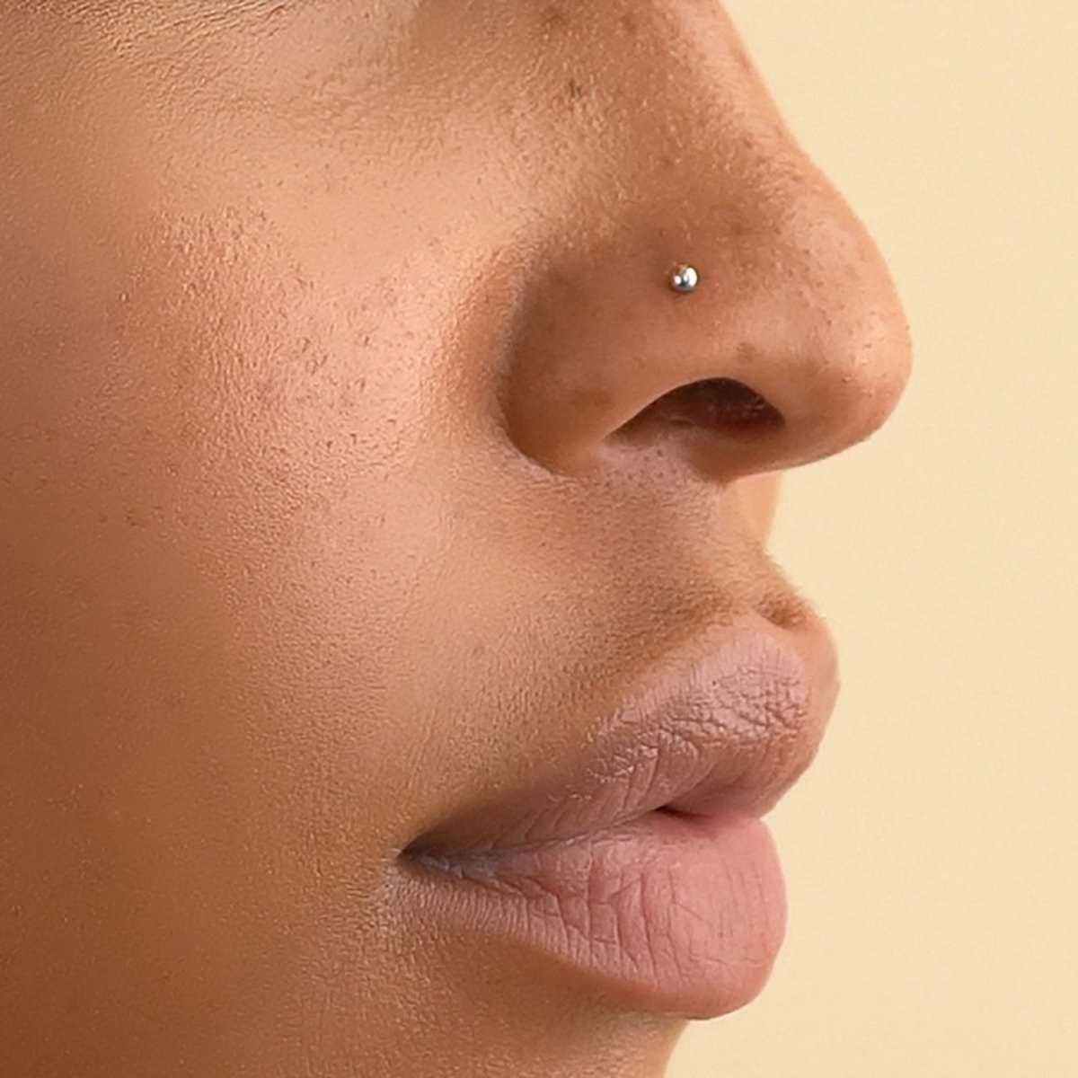 14K white gold ball nose stud shown close-up on a model's nostril in profile
