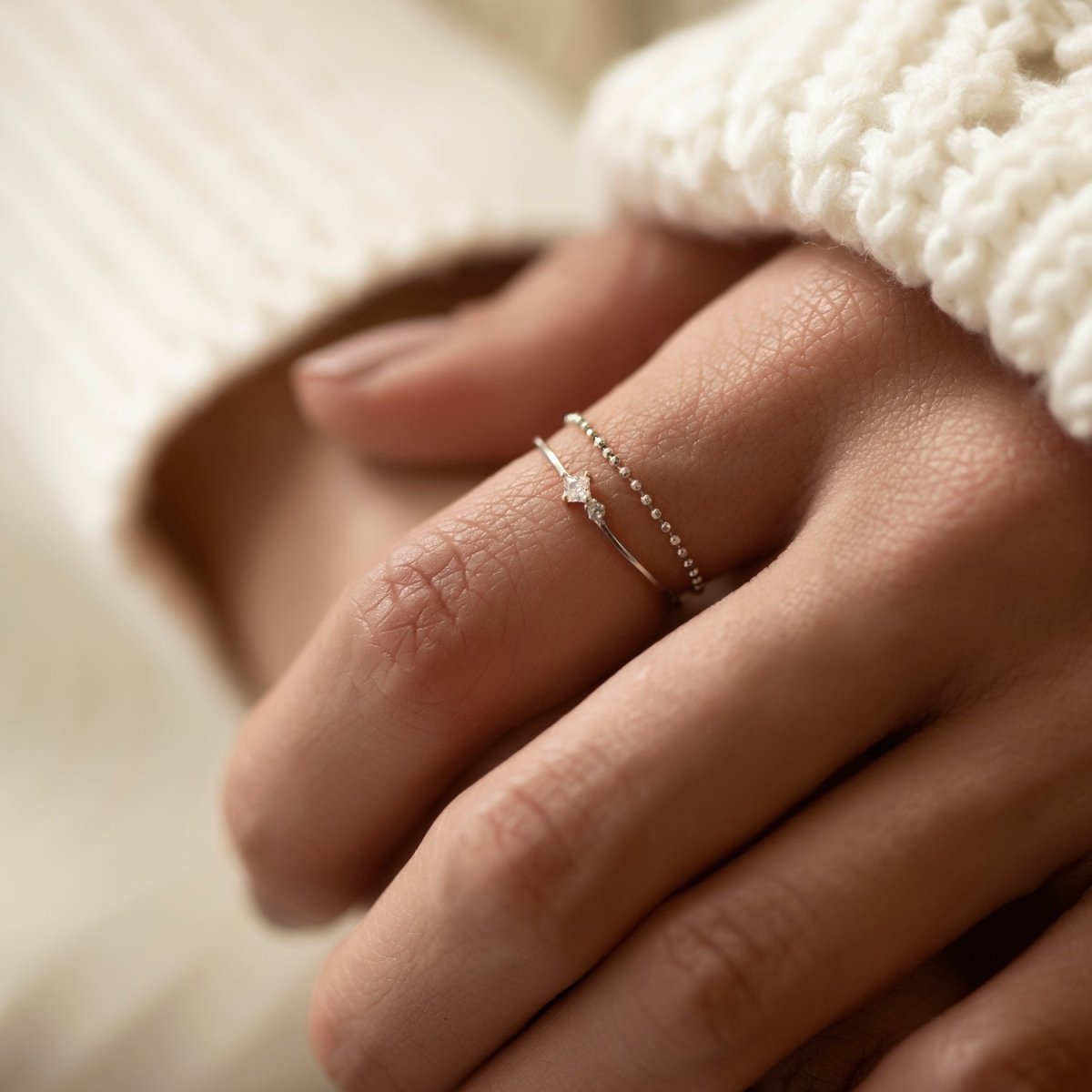 Sterling silver tiny duo ring stacked with a beaded band, shown on a model's finger