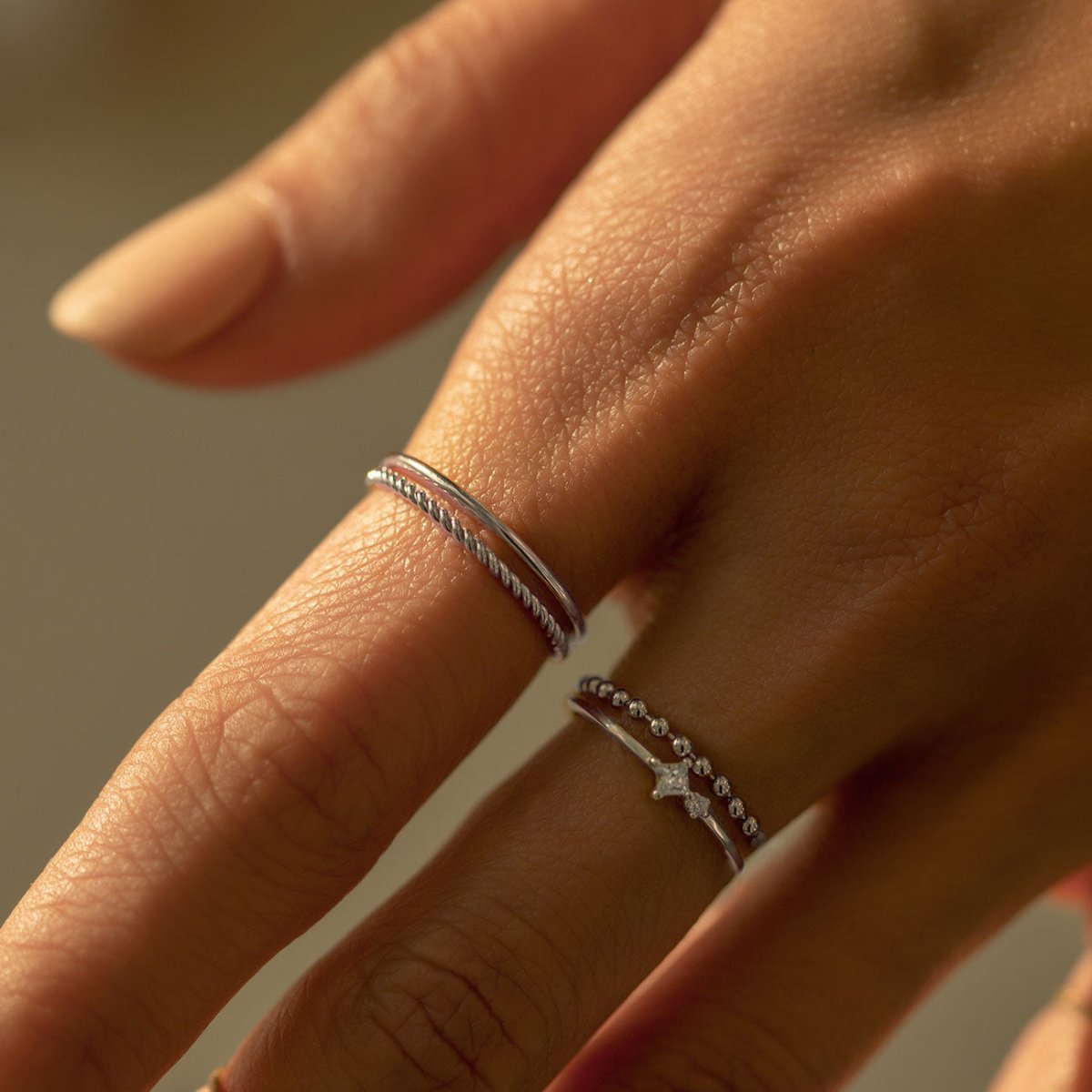 Sterling silver thin band and rope ring set, close-up of the stacked bands on a model's finger