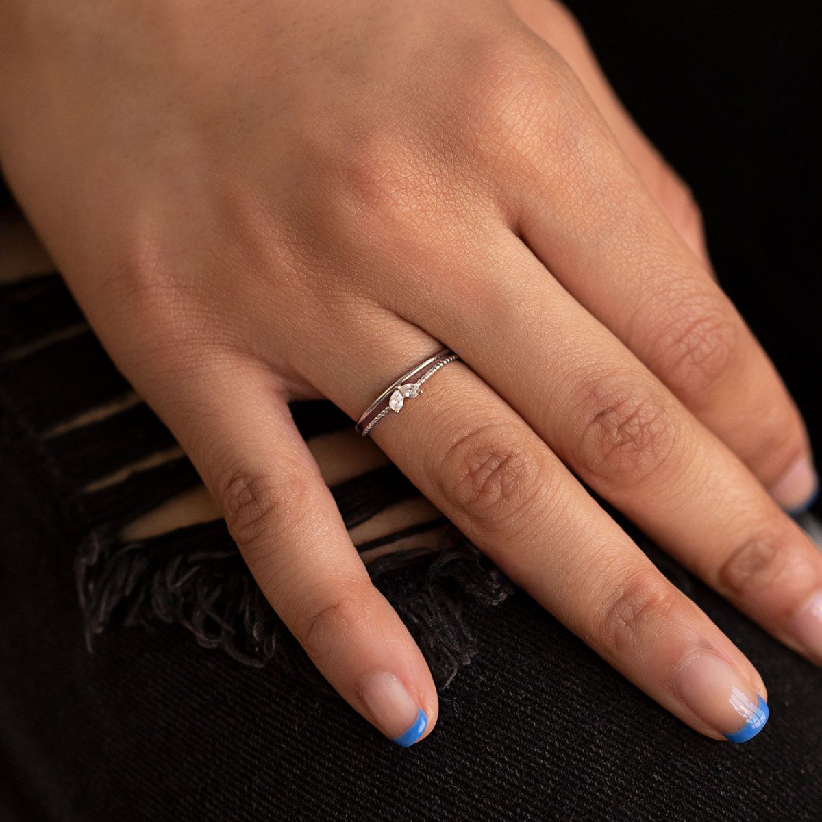 Sterling silver twin pear white zirconia ring worn on a model's finger against black denim