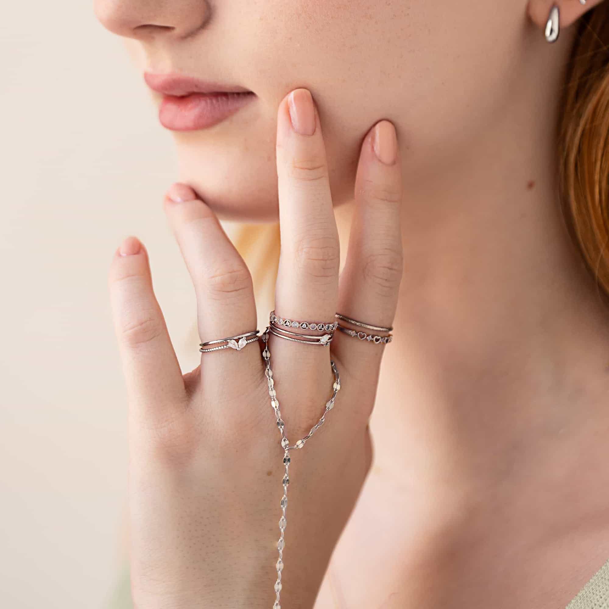 Silver stacking rings and a faceted hand chain shown on a model's hand