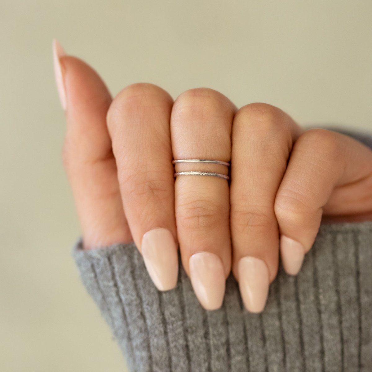 Sterling silver smooth and faceted stacking rings shown on a model's finger