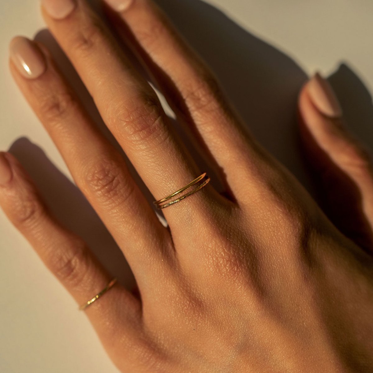 Gold-filled smooth and faceted stacking rings shown together on a model's finger