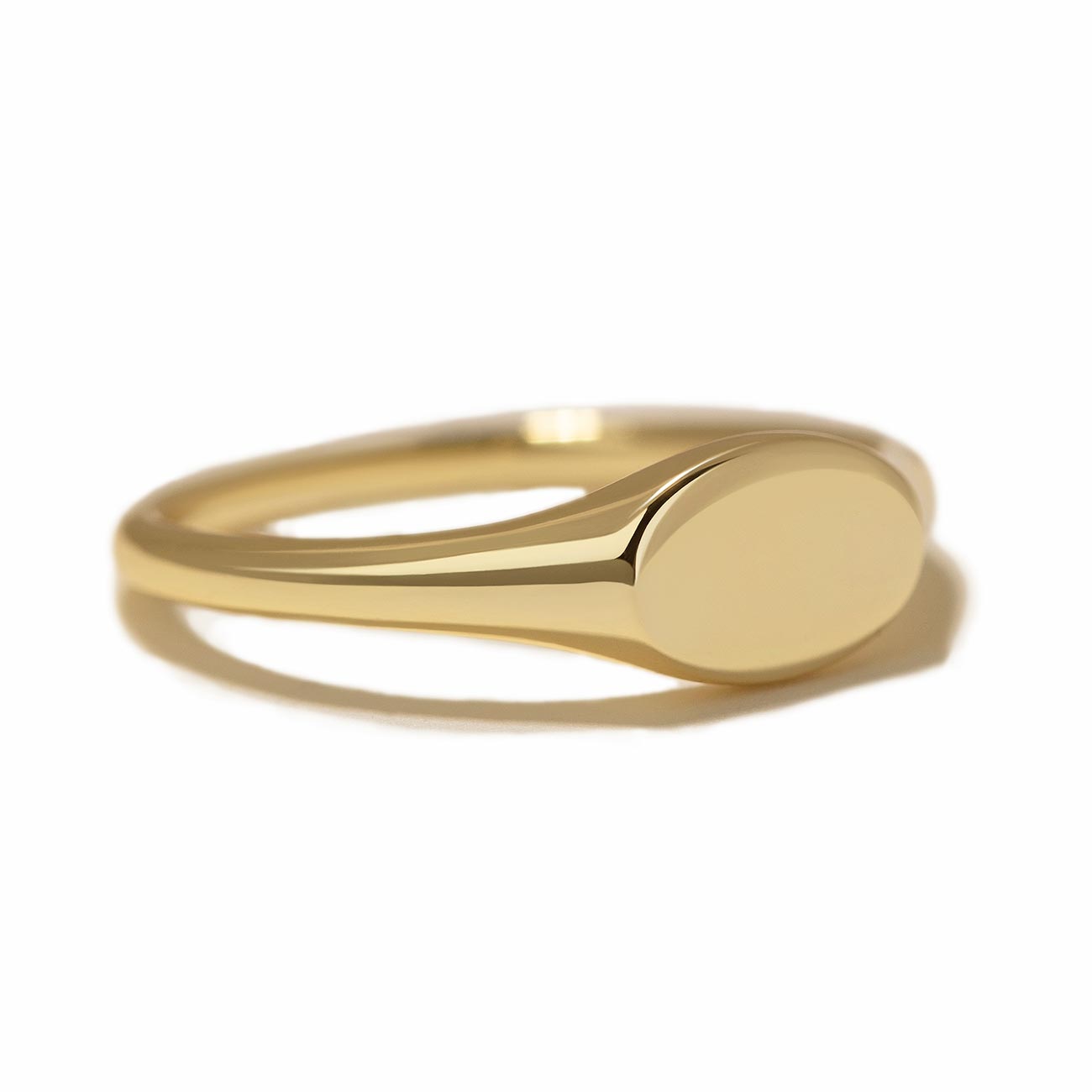 Gold vermeil oval signet ring with a plain polished face, on a white background