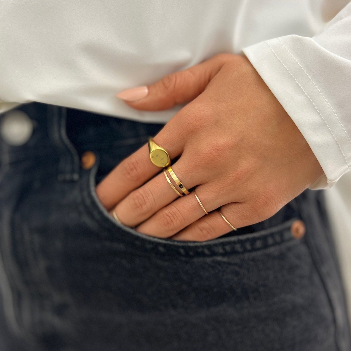 Gold-filled flat band ring worn on a hand tucked into a dark denim pocket
