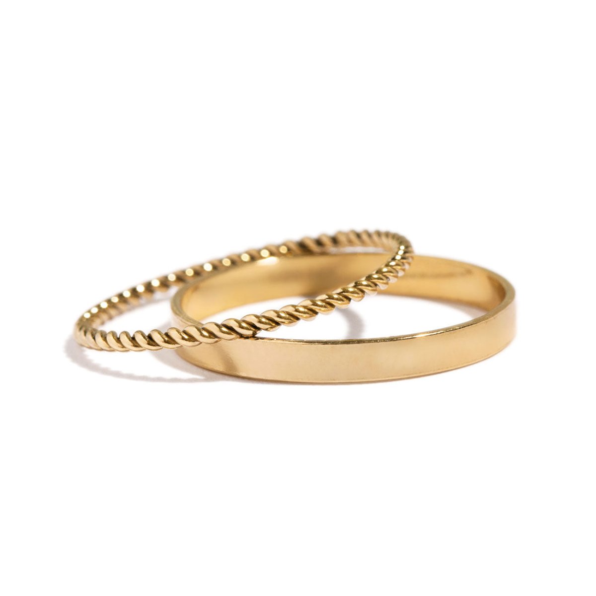 Gold-filled flat band and twisted rope band rings resting together, on a white background