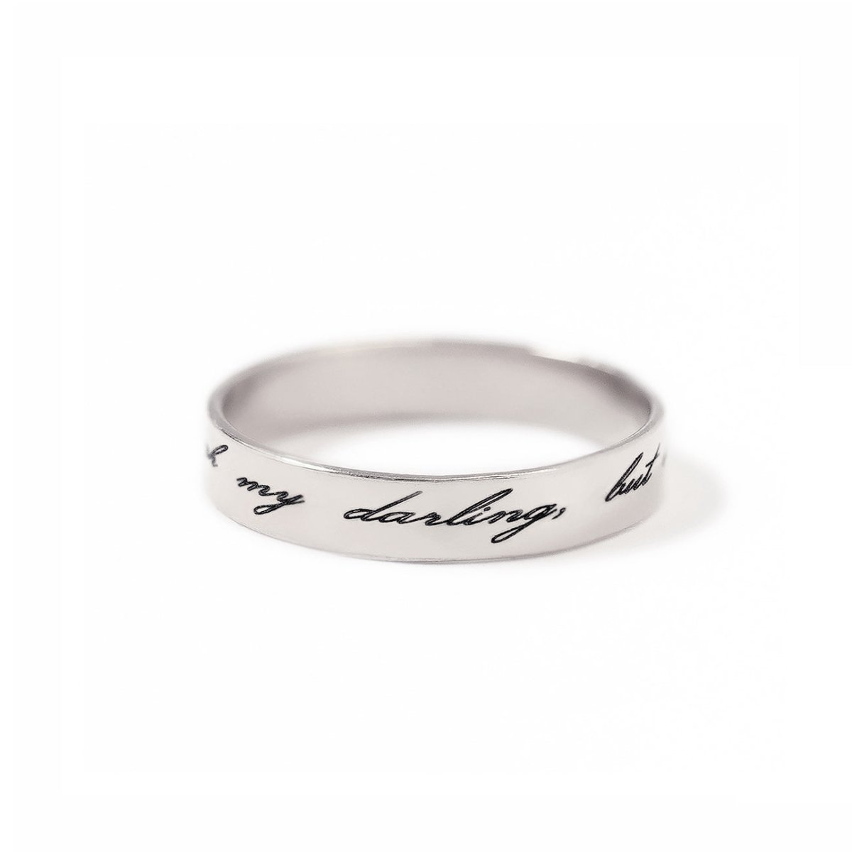 Sterling silver band ring engraved with a script message, on a white background