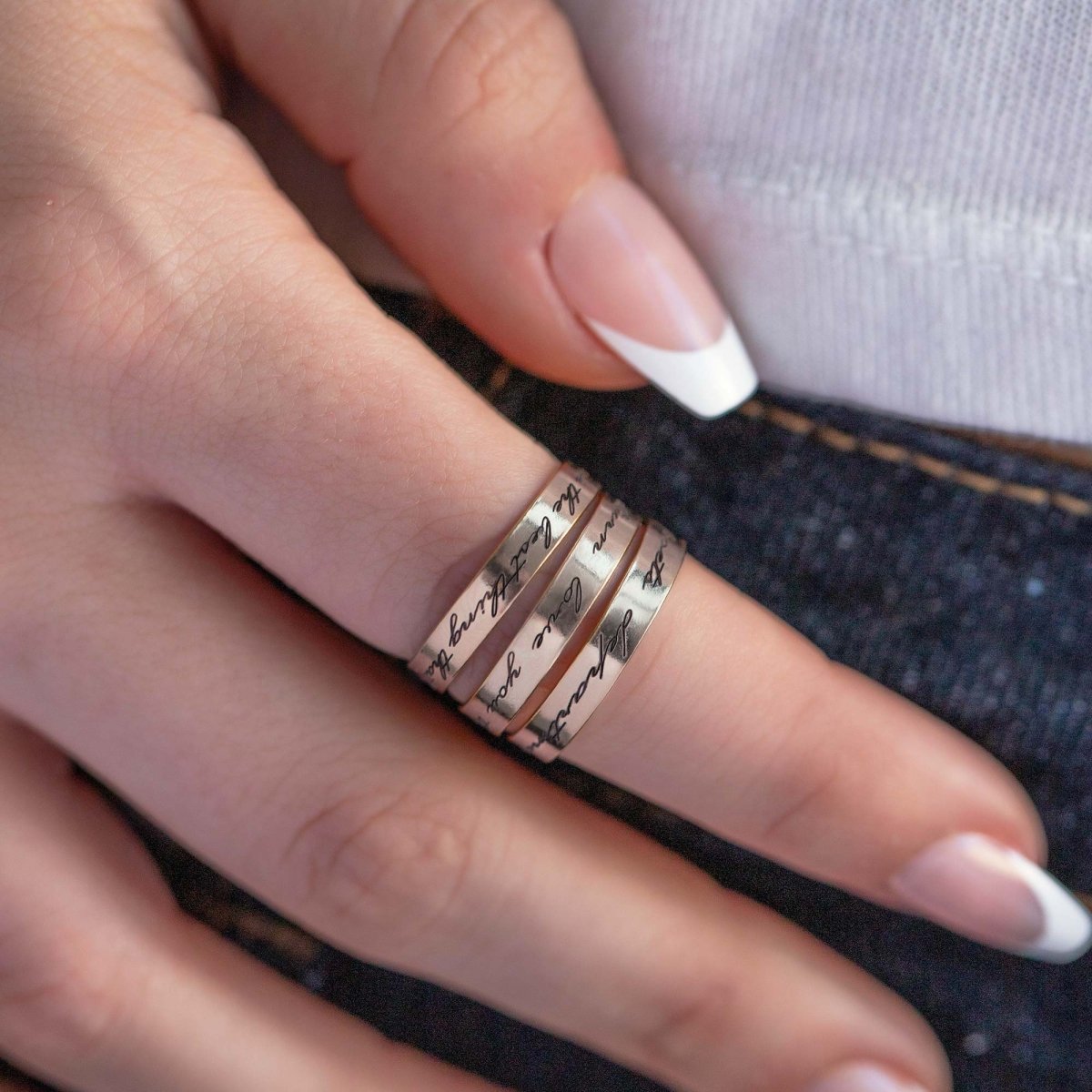 Sterling silver stacked band rings engraved with script messages, shown on a model's finger