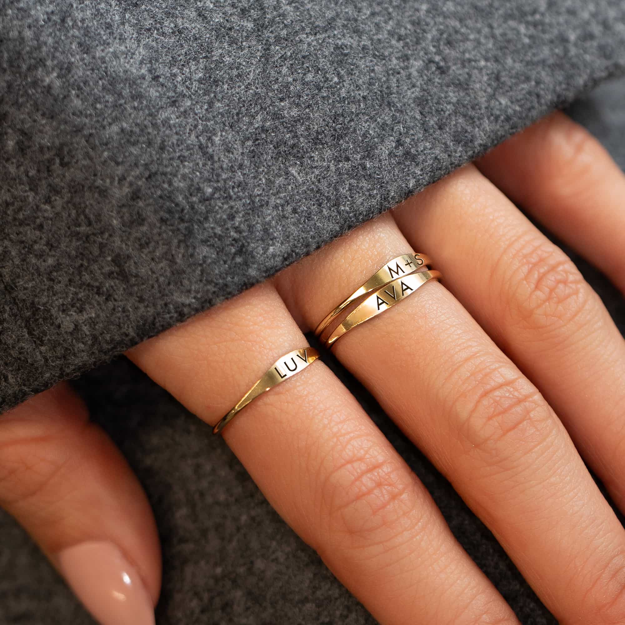 Gold-filled thin signet rings engraved with names, close-up stacked on a model's fingers
