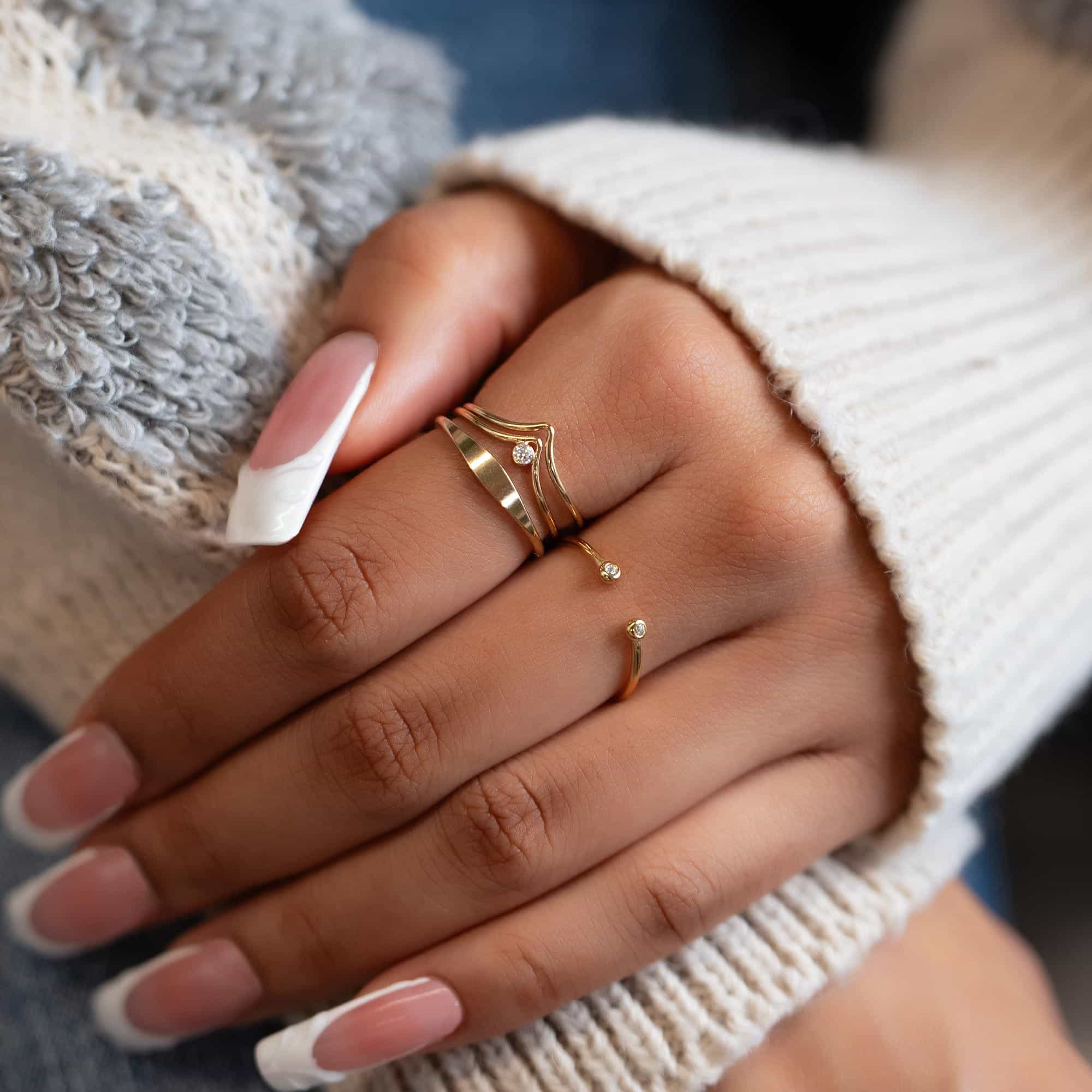 Gold-filled thin signet ring stacked among delicate gold rings, shown on a model's hand