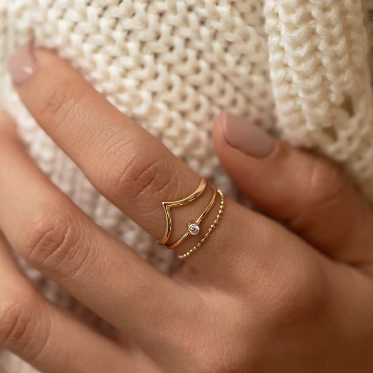 Gold-filled thin solitaire ring with a bezel-set white zirconia, shown on a model's finger