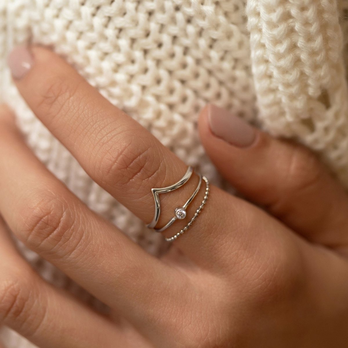 Sterling silver thin solitaire ring with a bezel-set white zirconia, shown on a model's finger