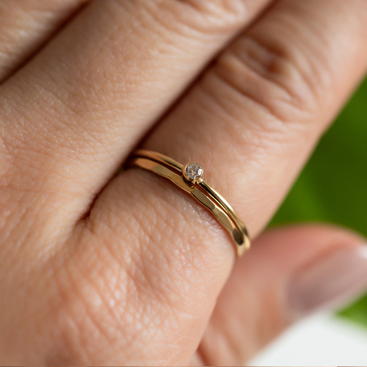 Gold-filled hammered band with a clear bezel-set stone, close-up detail on a model's finger