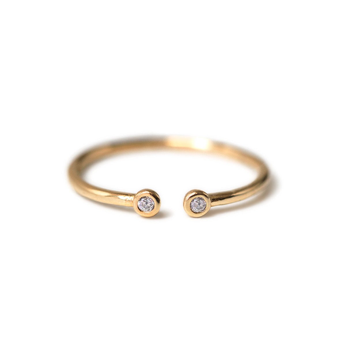 Gold vermeil open ring with two small clear stones at the tips, on a white background