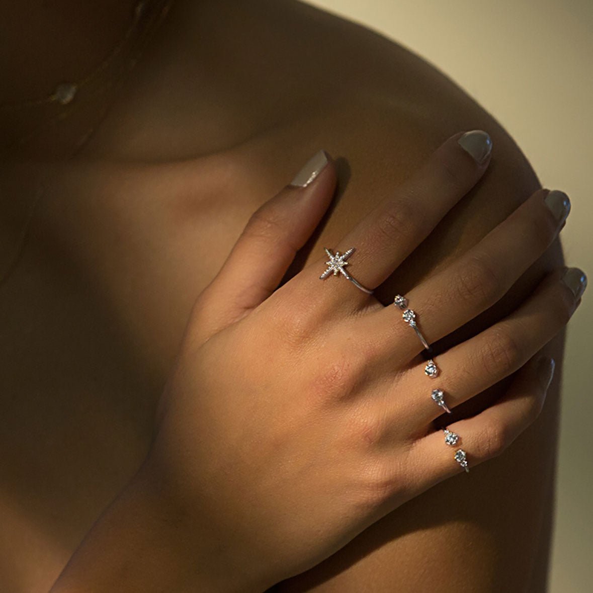 Sterling silver open cuff ring with clear zirconia stones, styled in a stack on a model's hand