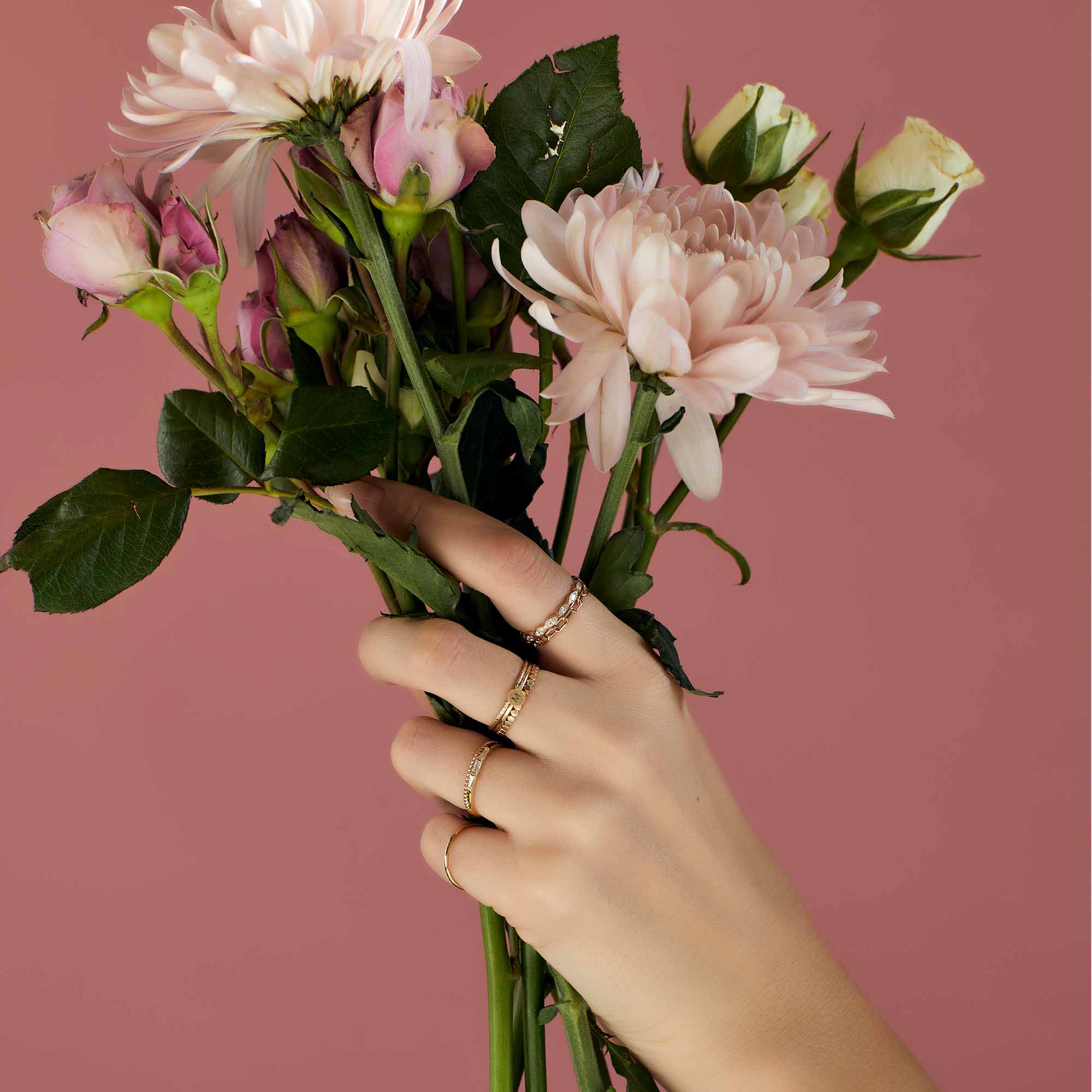 Gold vermeil baguette ring with clear stones, shown stacked on a hand holding flowers