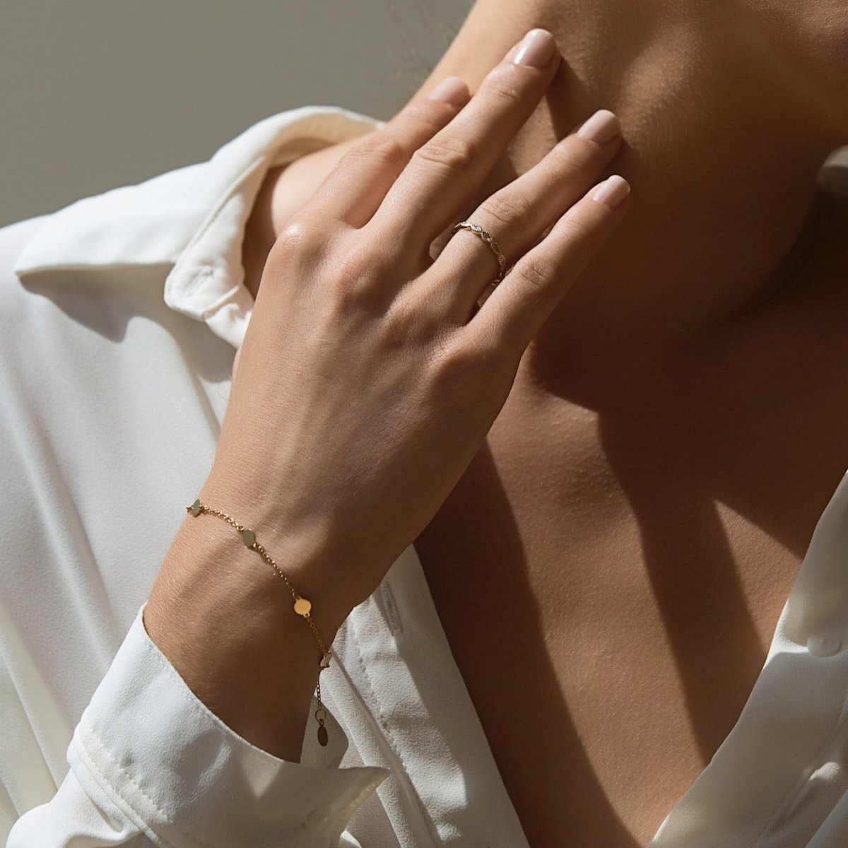 Gold vermeil round disc station bracelet with hanging tag, shown on a model's wrist