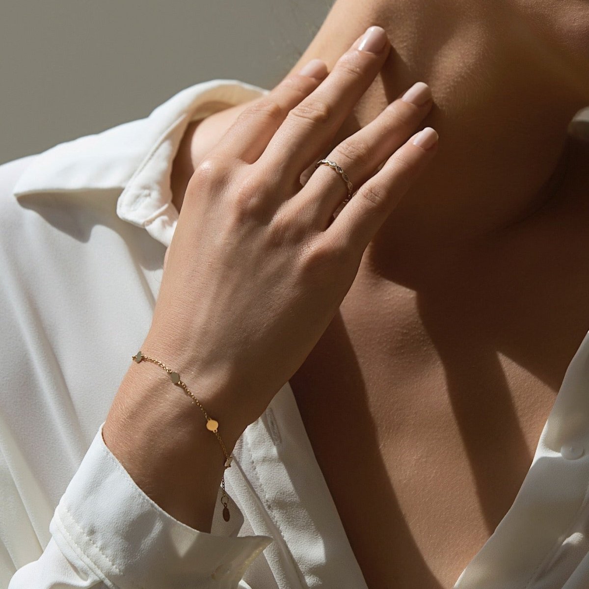 Rose gold vermeil round disc station bracelet with hanging tag, shown on a model's wrist