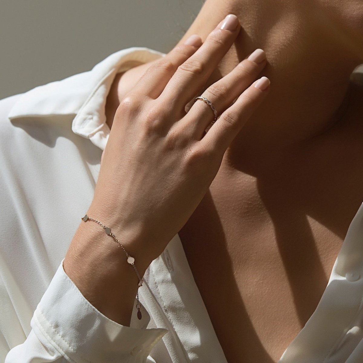 Sterling silver round disc station bracelet with hanging tag, shown on a model's wrist