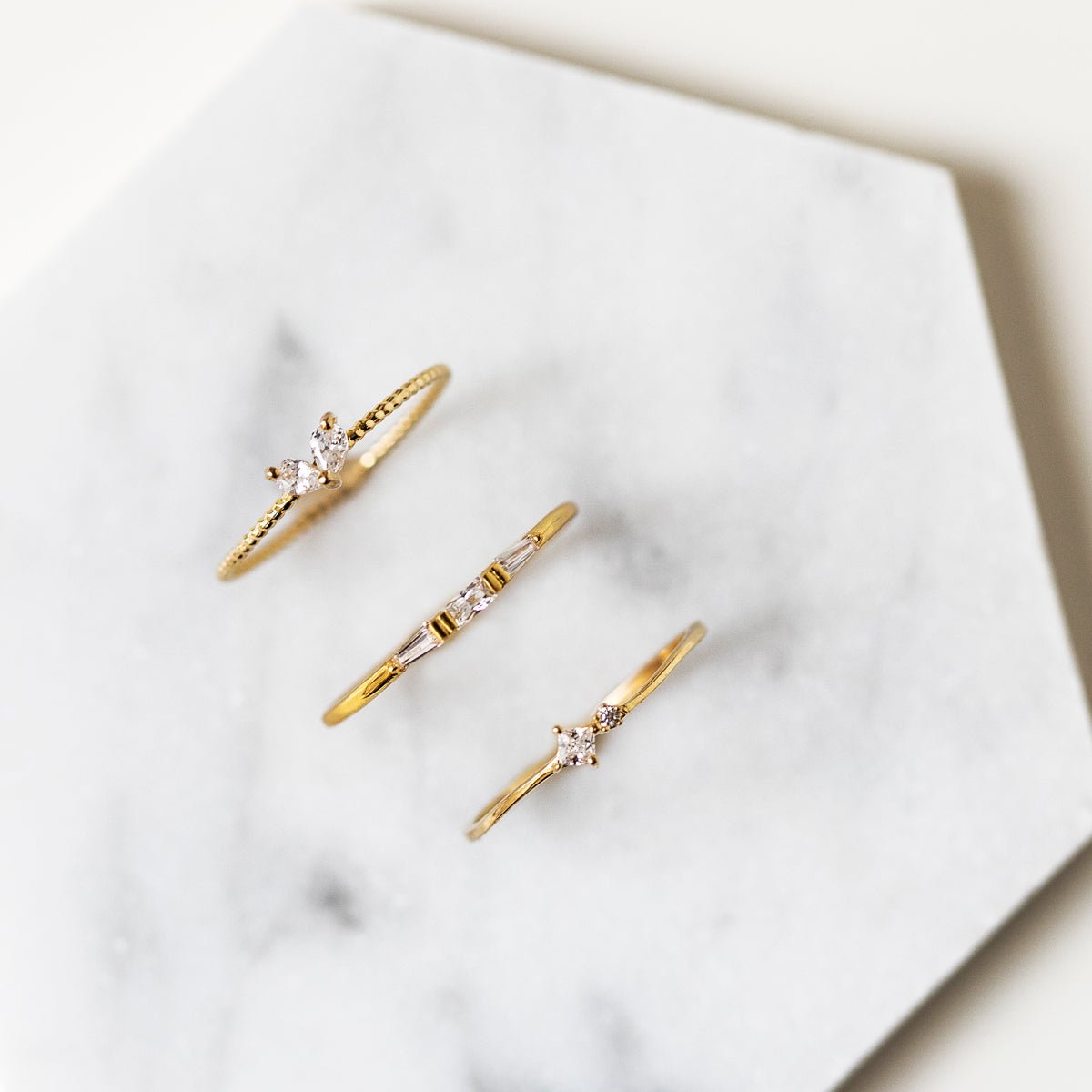 Gold vermeil baguette and round white zirconia rings shown on white marble