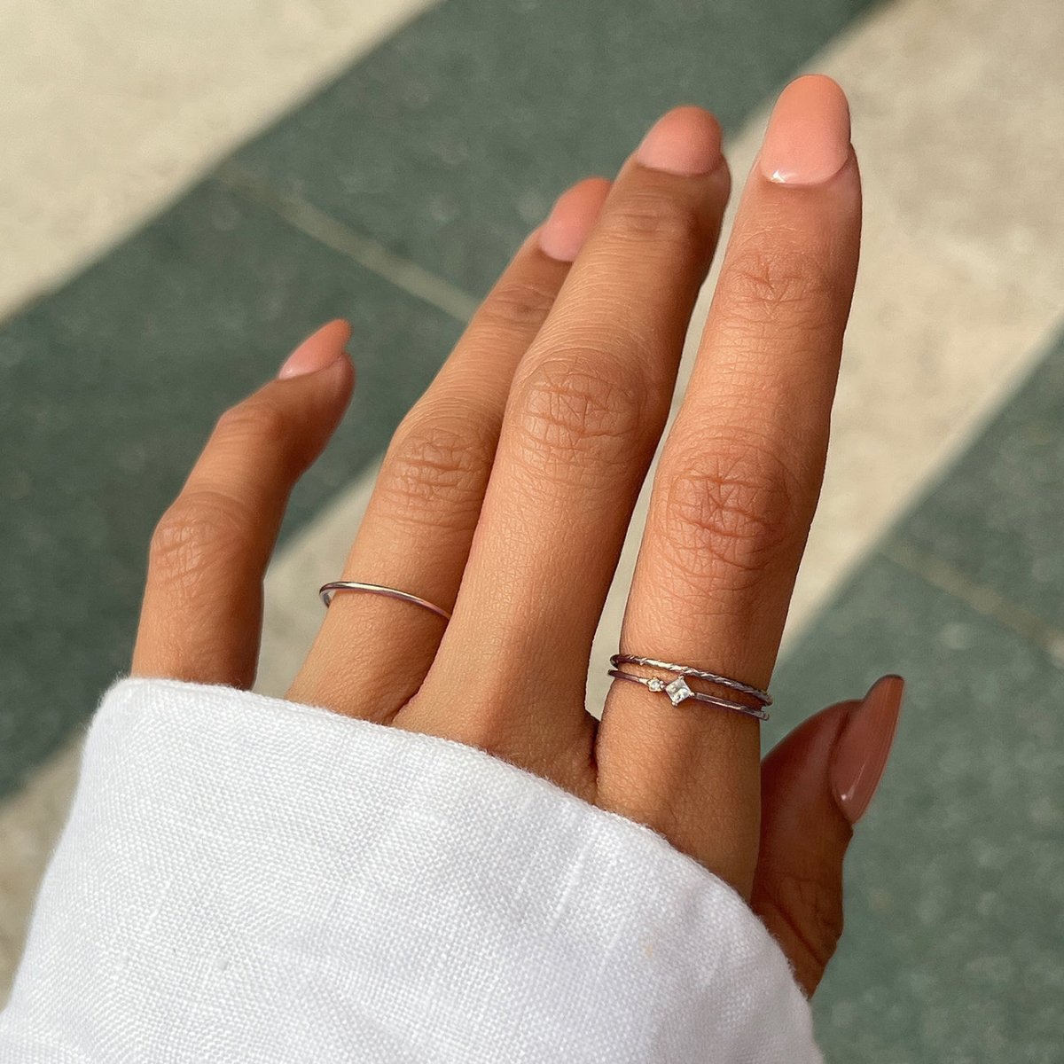 Sterling silver twisted and plain stacking rings with a white zirconia stone, on a model's finger