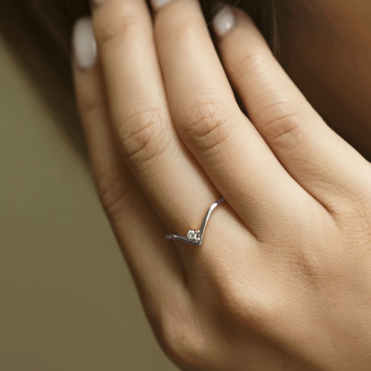 Sterling silver chevron ring with a single clear stone, close-up shown on a model's finger