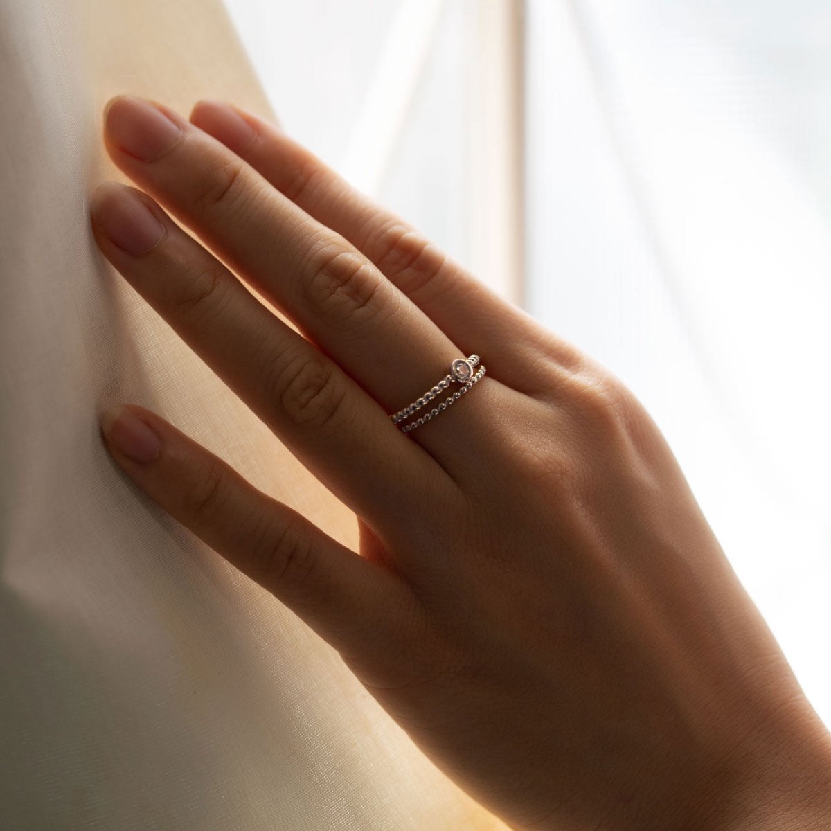 Sterling silver solitaire rope ring with a clear stone, shown on a model's finger
